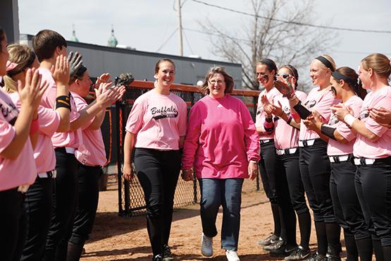 Maddie Coneys, left, walks with her mom, Pattie, who is a cancer survivor, before the Bengals’ ‘Strikeout Cancer’ game against Cortland on Friday. 