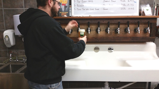 Rudy Watkins, head brewer at Community Beer Works, pours a pint glass of one of their brews.
