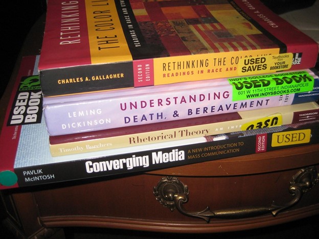 Stack of textbooks on students desk at home.