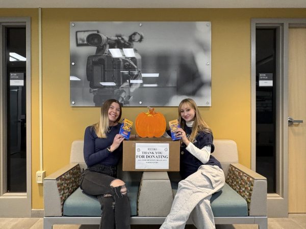 Record members Ally (L) and Charlotte (R) in front of the donation box outside of the Record Office, Buckham B141.